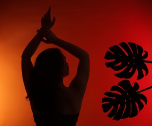 Photo of Silhouette of woman and tropical leaves on red gradient background
