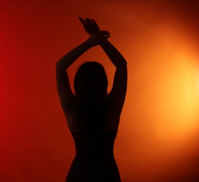 Photo of Silhouette of woman posing on red gradient background, back view