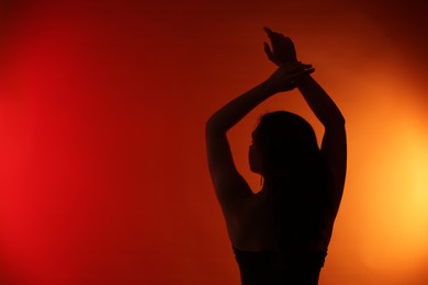 Photo of Silhouette of woman posing on red gradient background, back view. Space for text