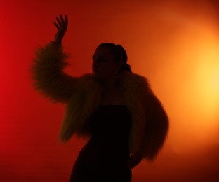 Photo of Silhouette of woman in stylish outfit posing on red gradient background