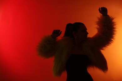 Photo of Silhouette of woman in stylish outfit posing on red gradient background, space for text