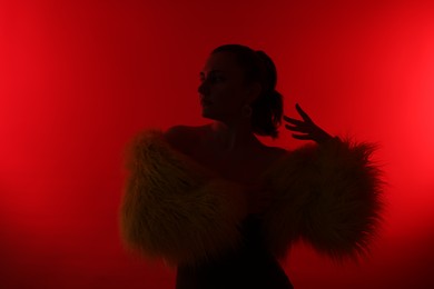 Photo of Silhouette of woman in stylish outfit posing on red background