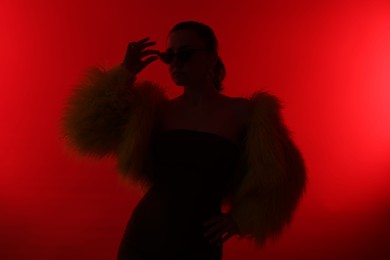 Photo of Silhouette of woman in stylish outfit posing on red background