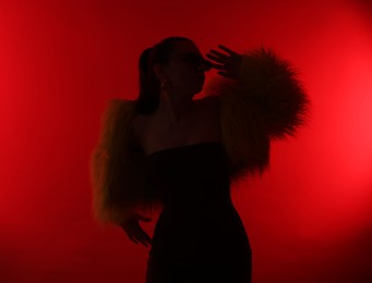 Photo of Silhouette of woman in stylish outfit posing on red background