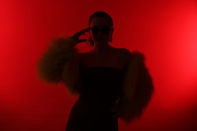 Photo of Silhouette of woman in stylish outfit posing on red background