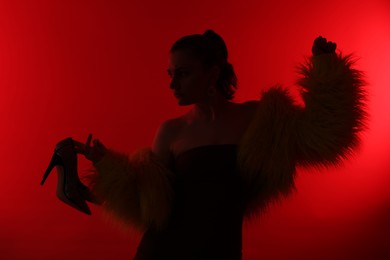Photo of Silhouette of woman in stylish outfit posing on red background