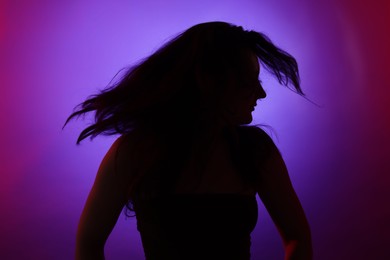 Photo of Silhouette of woman posing in neon lights on color background