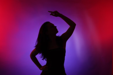 Photo of Silhouette of woman posing in neon lights on color background