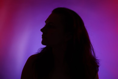 Photo of Silhouette of woman posing in neon lights on color background