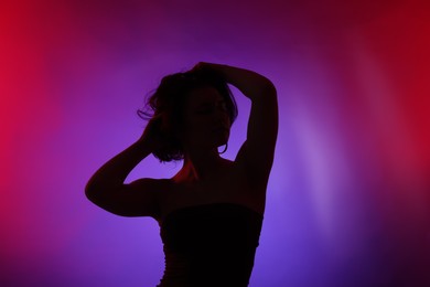 Photo of Silhouette of woman posing in neon lights on color background
