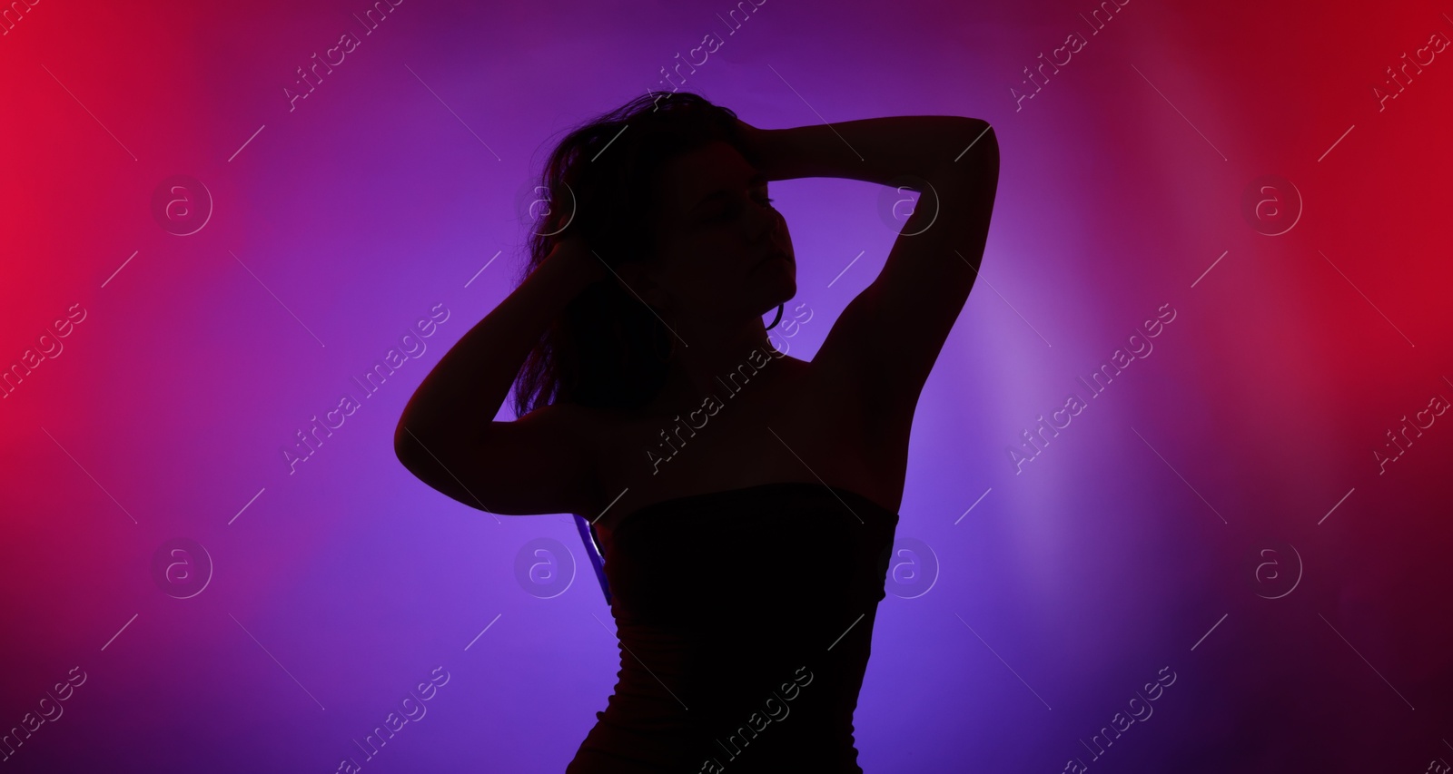 Photo of Silhouette of woman posing in neon lights on color background