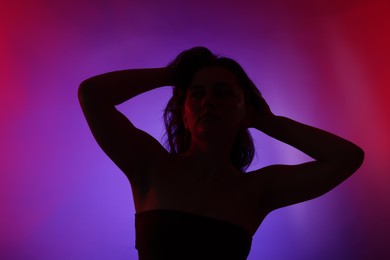 Photo of Silhouette of woman posing in neon lights on color background