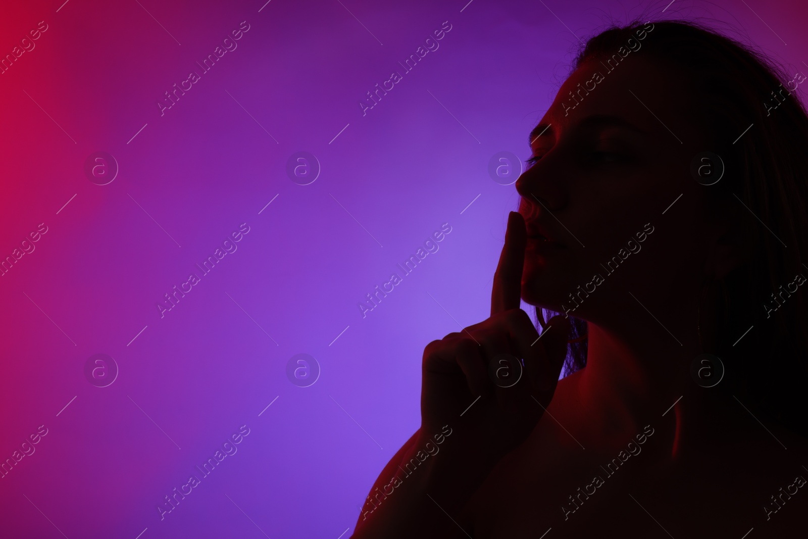 Silhouette of woman making silent gesture in neon lights on color background, space for text Photo of Silhouette of woman making silent gesture in neon lights on color background, space for text