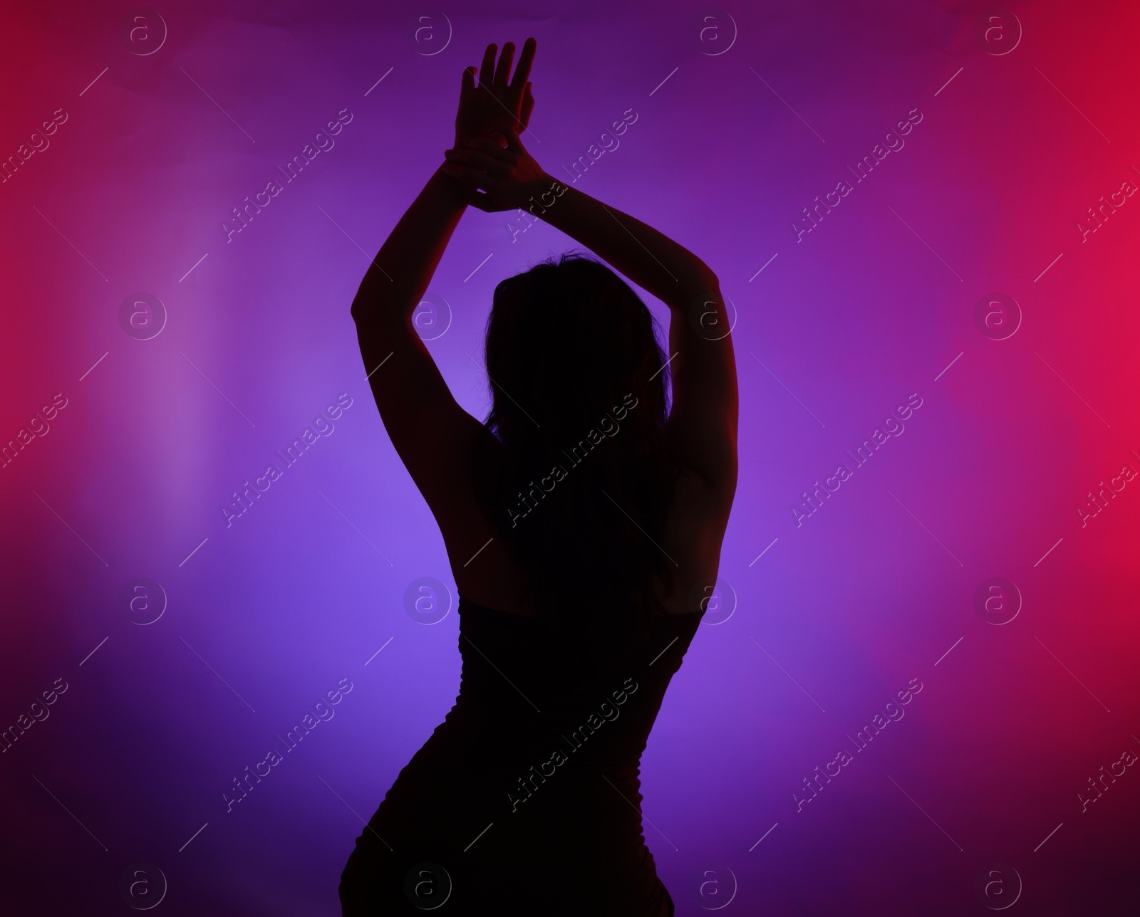 Photo of Silhouette of woman posing in neon lights on color background, back view
