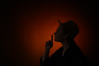 Photo of Silhouette of woman making silent gesture on dark gradient background, space for text