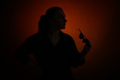 Photo of Silhouette of woman with sunglasses on dark gradient background