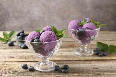Photo of Tasty sorbet with blueberries and mint in dessert bowls on wooden table against grey background, closeup