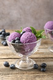 Photo of Tasty sorbet with blueberries and mint in dessert bowl on wooden table against grey background, closeup