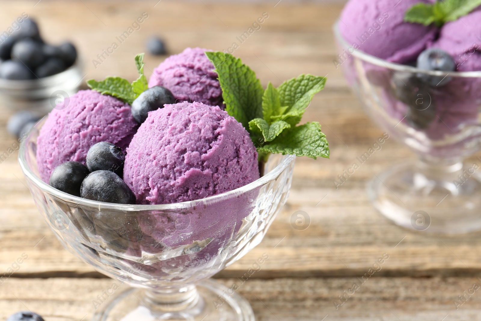 Tasty sorbet with blueberries and mint in dessert bowls on wooden table, closeup Photo of Tasty sorbet with blueberries and mint in dessert bowls on wooden table, closeup