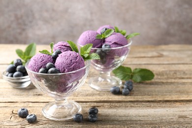 Photo of Tasty sorbet with blueberries and mint in dessert bowls on wooden table against grey background, closeup
