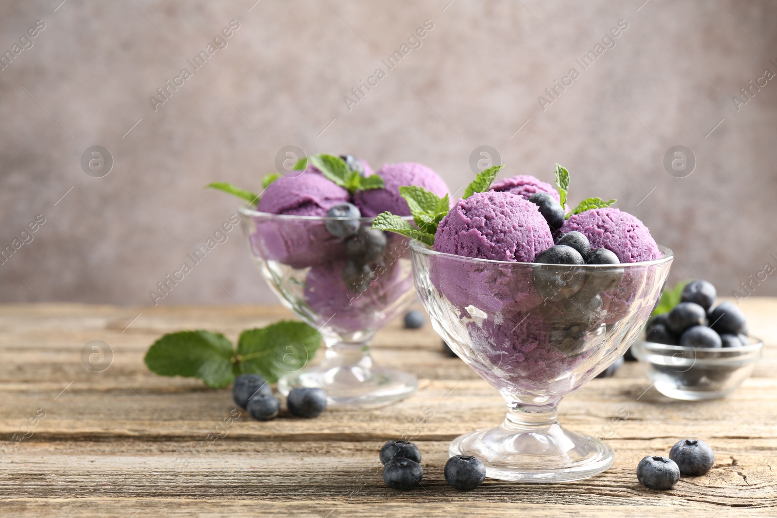 Tasty sorbet with blueberries and mint in dessert bowls on wooden table against grey background, closeup Photo of Tasty sorbet with blueberries and mint in dessert bowls on wooden table against grey background, closeup