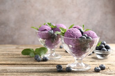 Photo of Tasty sorbet with blueberries and mint in dessert bowls on wooden table against grey background, closeup