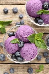 Photo of Tasty sorbet with blueberries and mint in dessert bowls on wooden table, flat lay