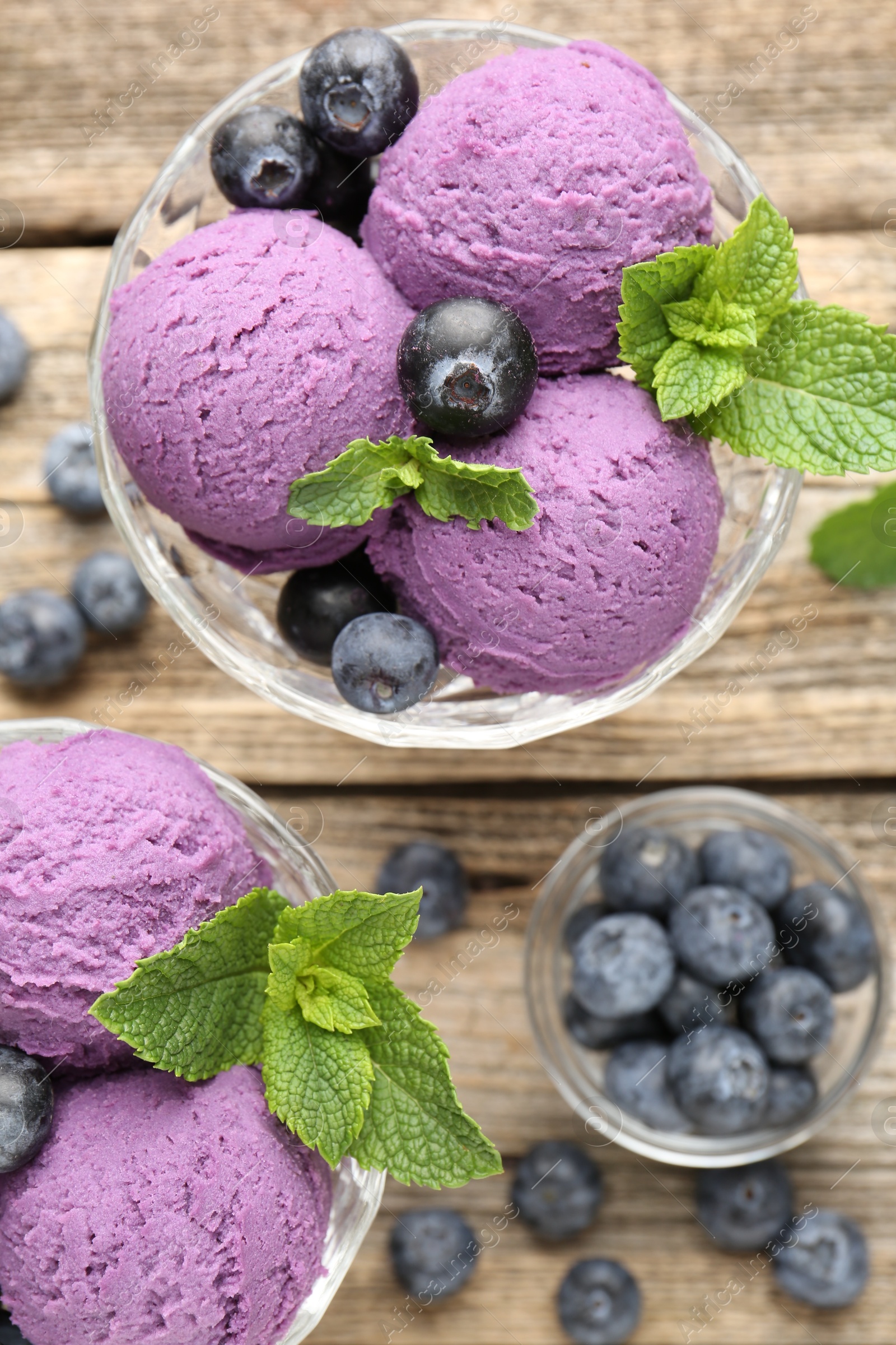 Tasty sorbet with blueberries and mint in dessert bowls on wooden table, flat lay Photo of Tasty sorbet with blueberries and mint in dessert bowls on wooden table, flat lay