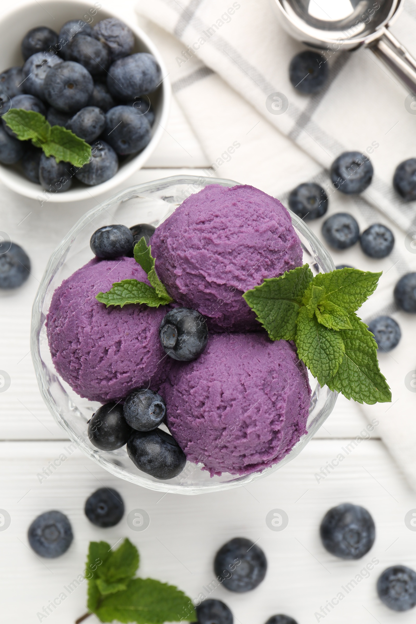Photo of Tasty sorbet with blueberries and mint in dessert bowl on white wooden table, flat lay