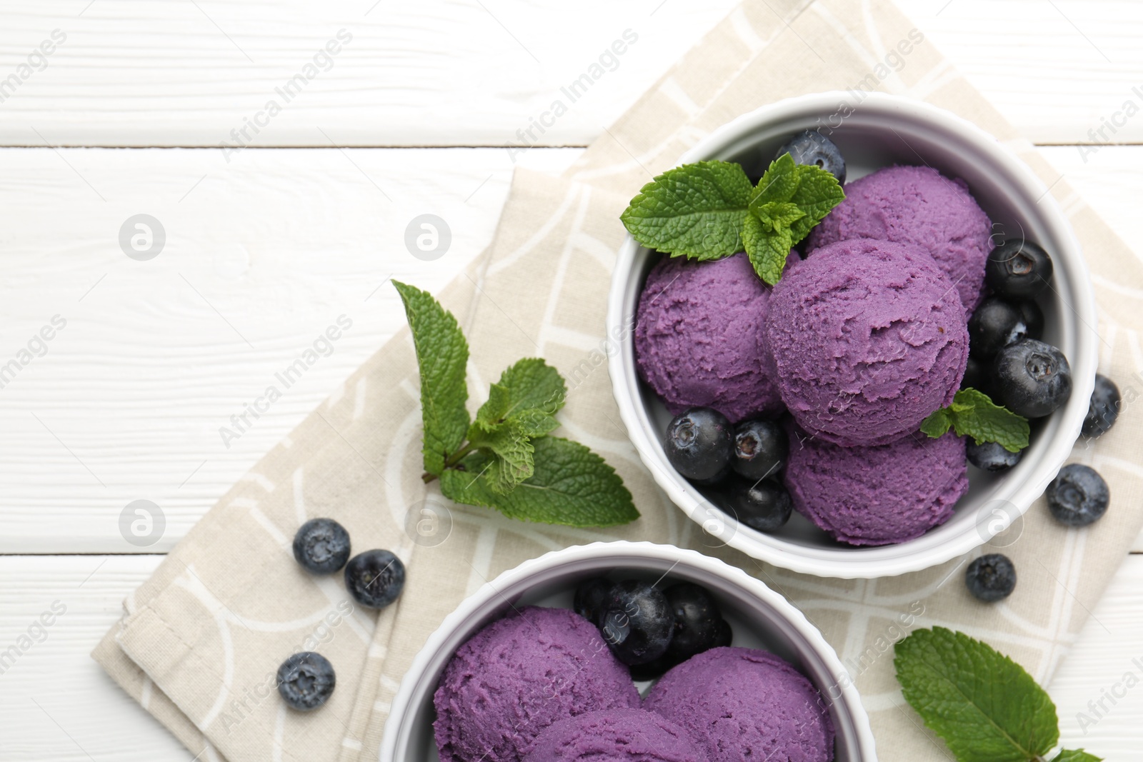 Tasty sorbet with blueberries and mint in bowls on white wooden table, top view Photo of Tasty sorbet with blueberries and mint in bowls on white wooden table, top view