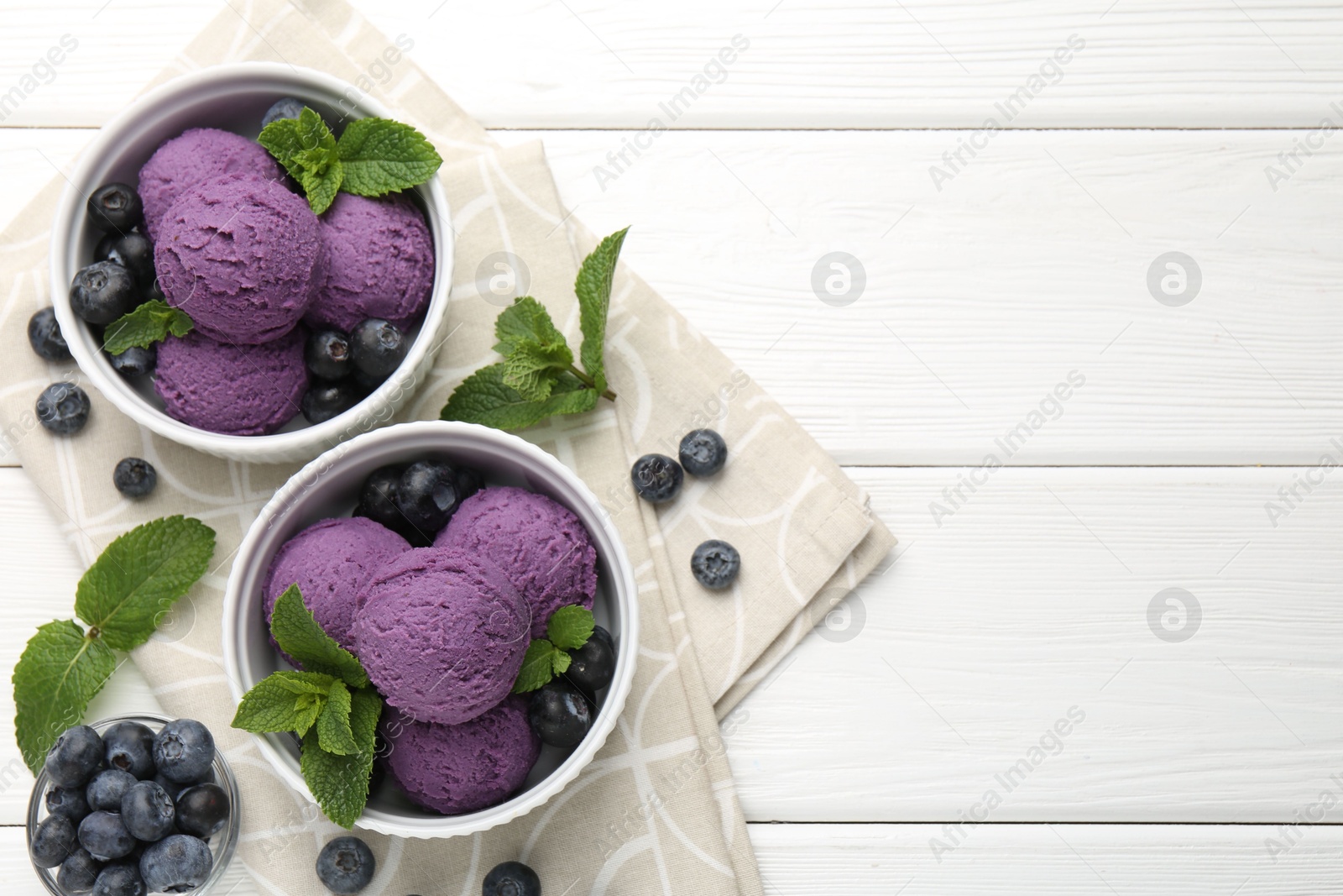 Photo of Tasty sorbet with blueberries and mint in bowls on white wooden table, top view. Space for text