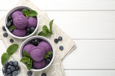 Photo of Tasty sorbet with blueberries and mint in bowls on white wooden table, top view. Space for text