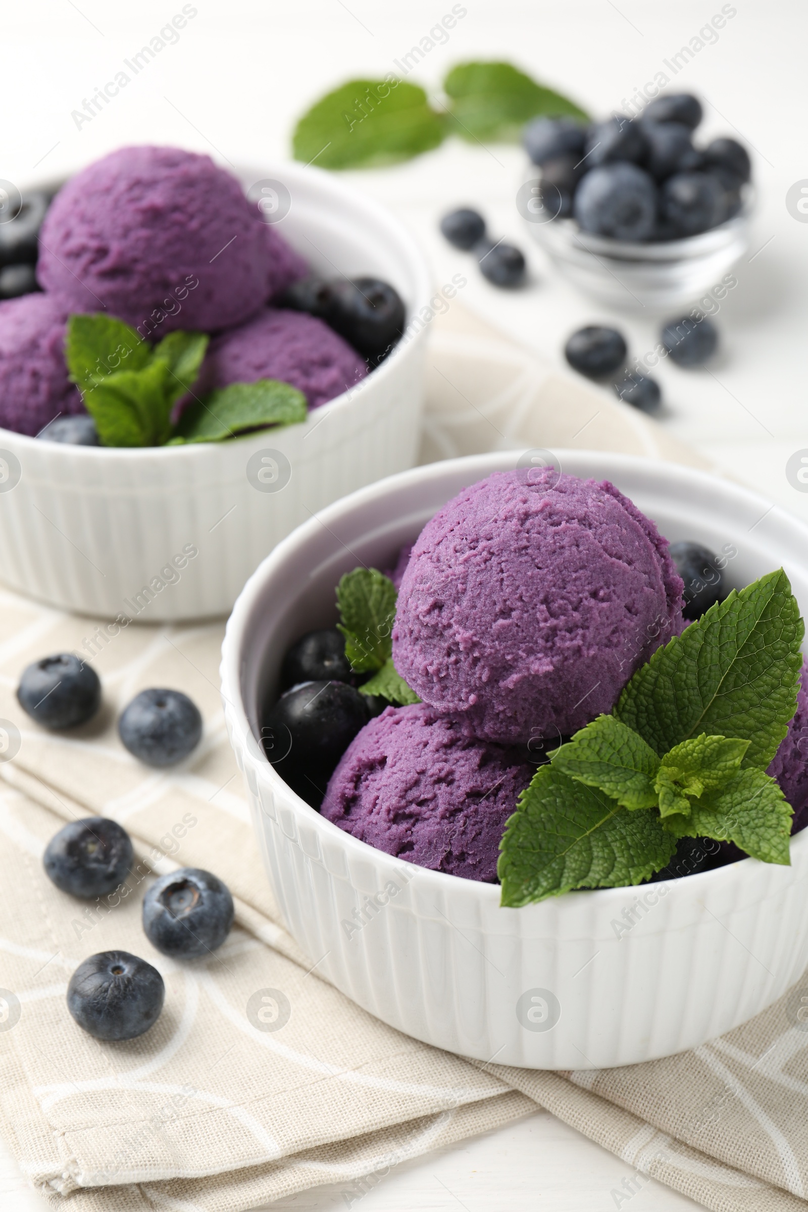 Photo of Tasty sorbet with blueberries and mint in bowls on white table, closeup