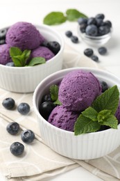 Photo of Tasty sorbet with blueberries and mint in bowls on white table, closeup