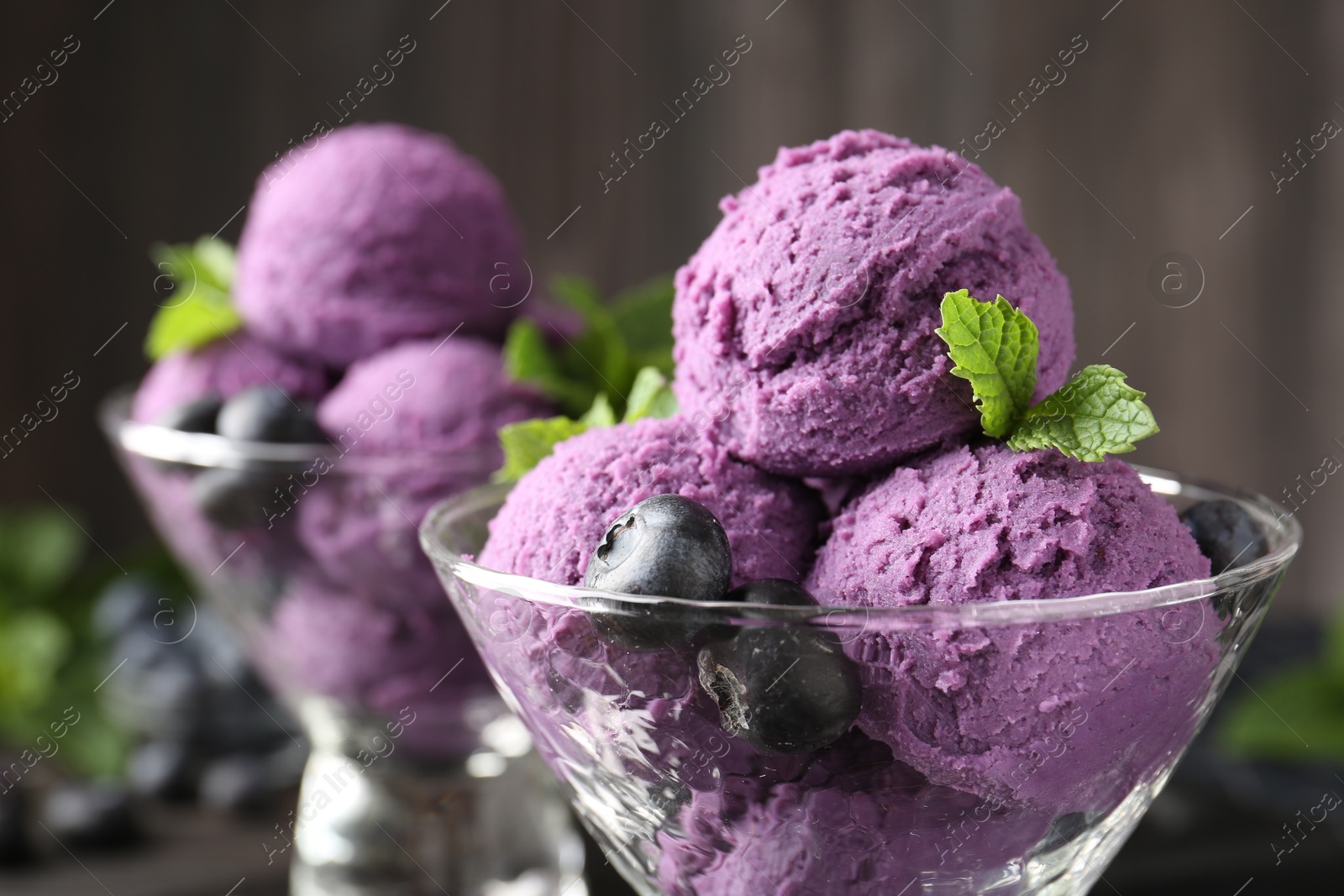 Tasty sorbet with blueberries and mint in dessert bowls against blurred background, closeup Photo of Tasty sorbet with blueberries and mint in dessert bowls against blurred background, closeup