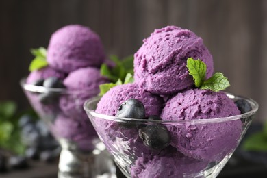 Photo of Tasty sorbet with blueberries and mint in dessert bowls against blurred background, closeup