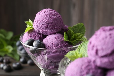 Photo of Tasty sorbet with blueberries and mint in dessert bowl on table against blurred background, closeup