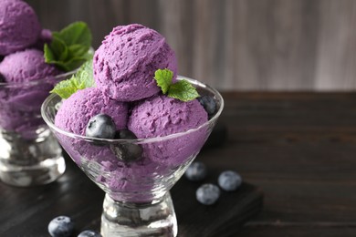 Photo of Tasty sorbet with blueberries and mint in dessert bowls on wooden table, closeup. Space for text