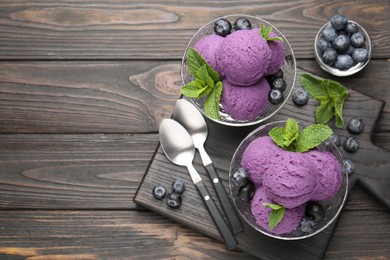 Photo of Tasty sorbet with blueberries and mint in dessert bowls on wooden table, flat lay. Space for text