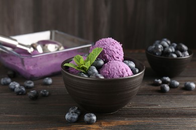 Photo of Tasty sorbet with blueberries and mint in bowl on wooden table, closeup