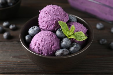 Photo of Tasty sorbet with blueberries and mint in bowl on wooden table, closeup
