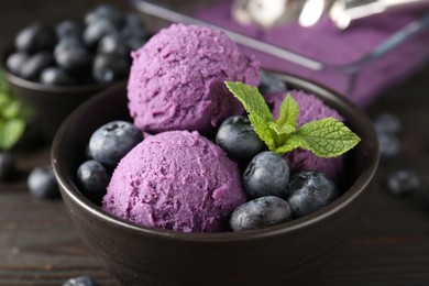 Photo of Tasty sorbet with blueberries and mint in bowl on wooden table, closeup