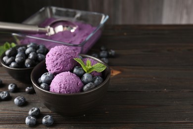 Photo of Tasty sorbet with blueberries and mint in bowl on wooden table, closeup. Space for text