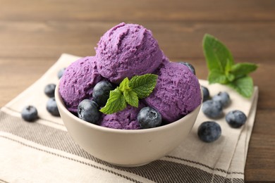 Photo of Tasty sorbet with blueberries and mint in bowl on wooden table, closeup