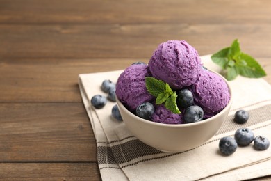 Photo of Tasty sorbet with blueberries and mint in bowl on wooden table, closeup. Space for text
