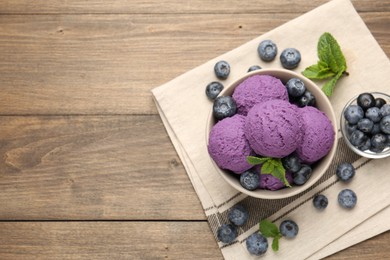 Photo of Tasty sorbet with blueberries and mint in bowl on wooden table, top view. Space for text