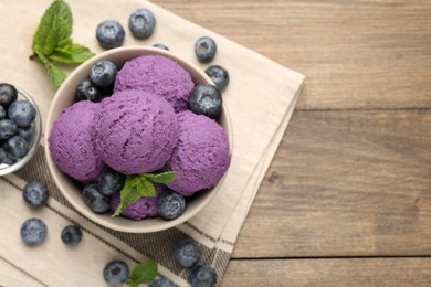 Photo of Tasty sorbet with blueberries and mint in bowl on wooden table, top view. Space for text