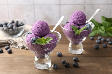 Photo of Tasty sorbet with blueberries and mint in dessert bowls on wooden table, closeup