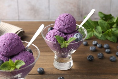 Photo of Tasty sorbet with blueberries and mint in dessert bowls on wooden table, closeup