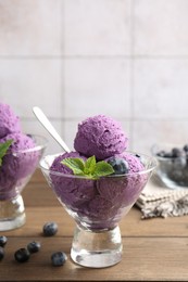 Photo of Tasty sorbet with blueberries and mint in dessert bowls on wooden table against tiled background, closeup